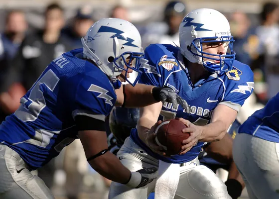 A handoff in the backfield during a college football game.