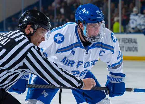 Play along the boards in a college hockey game.